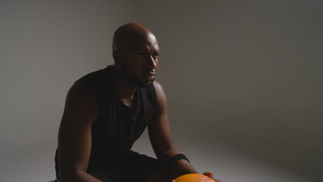 Studio-Shot-Of-Seated-Male-Basketball-Player-With-Hands-Holding-Ball-4